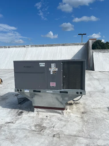 Large commercial HVAC unit on a flat roof under blue sky with clouds