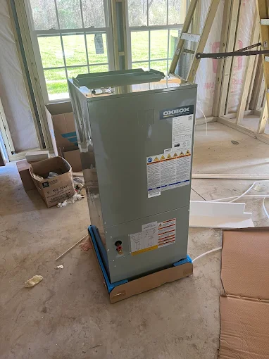OXXO brand HVAC unit in unfinished room with windows and construction materials