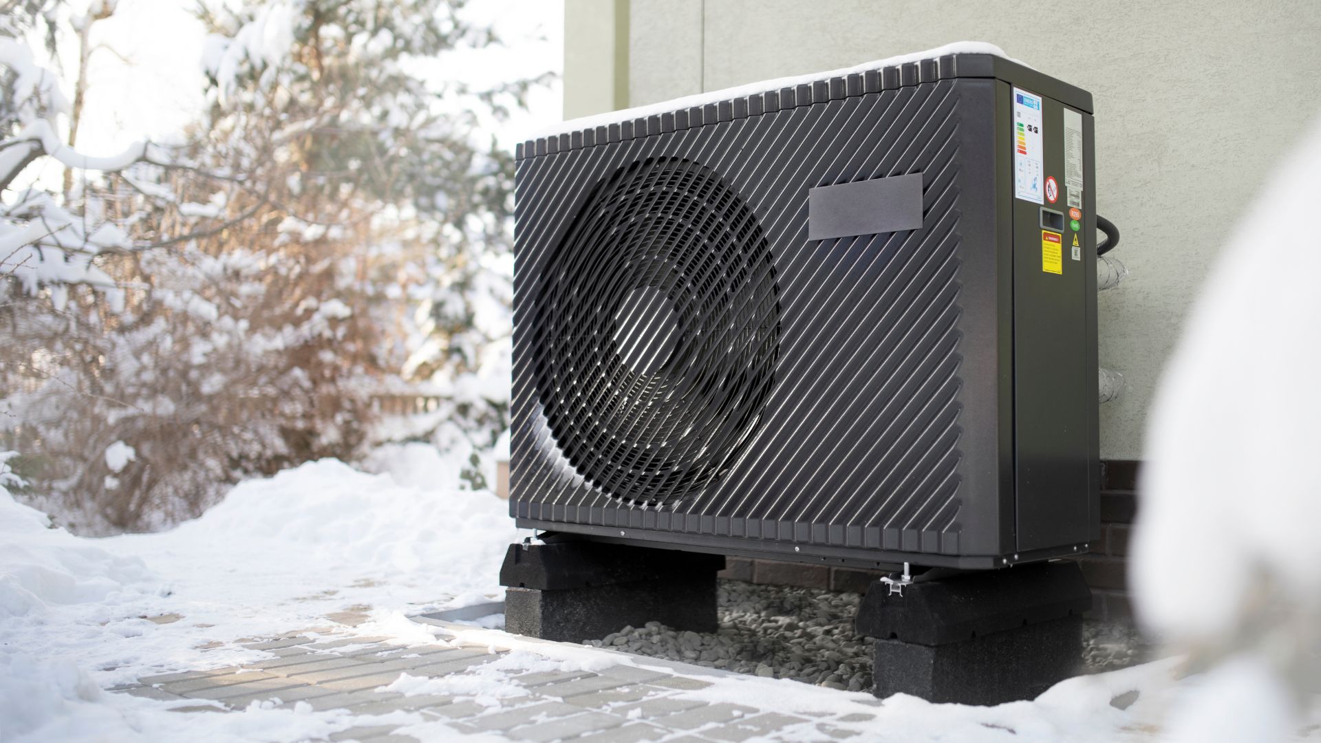 Heat pump installed outside in snowy winter landscape