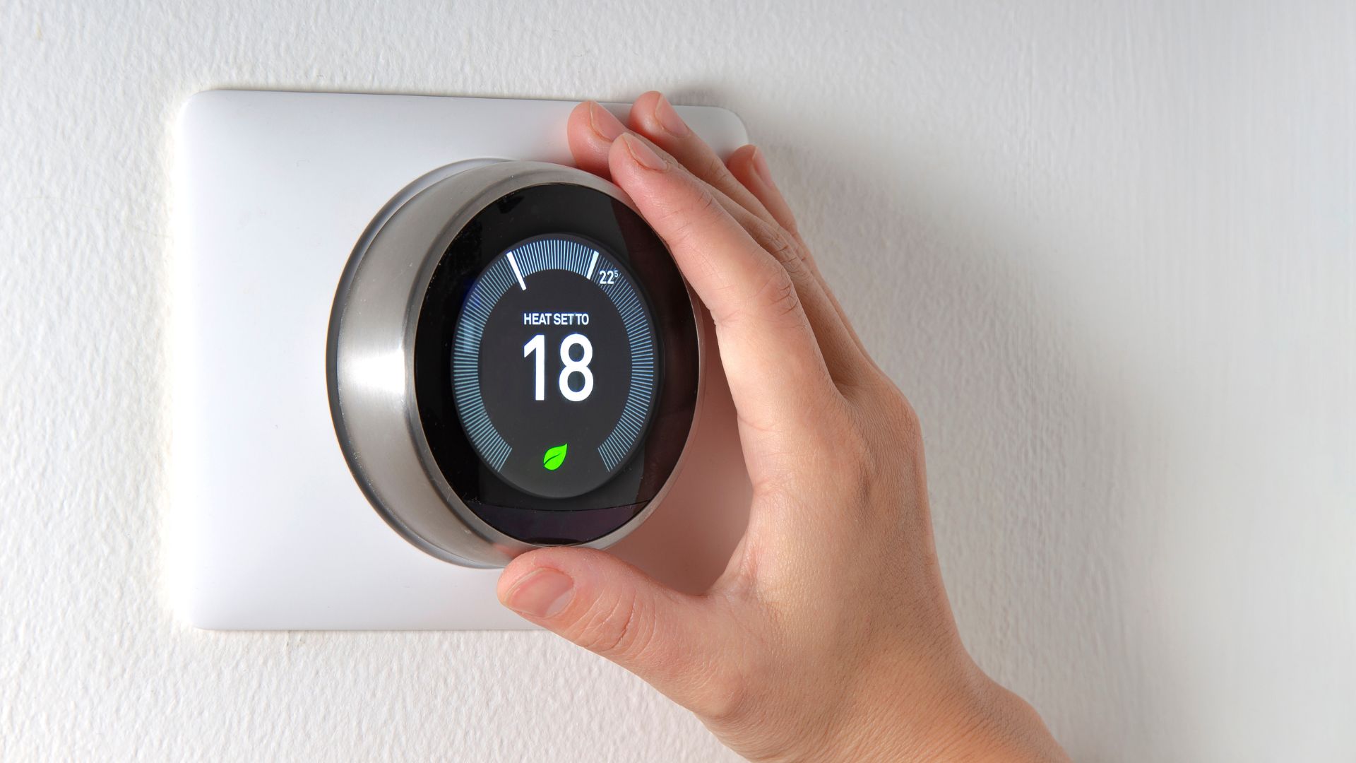 Smart thermostat being adjusted to 18 degrees with eco-friendly leaf icon