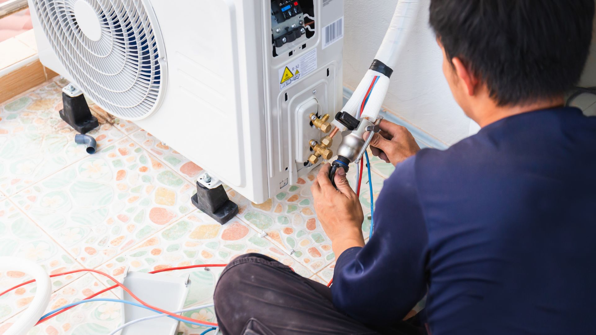 Technician installing or repairing an air conditioning unit with tools