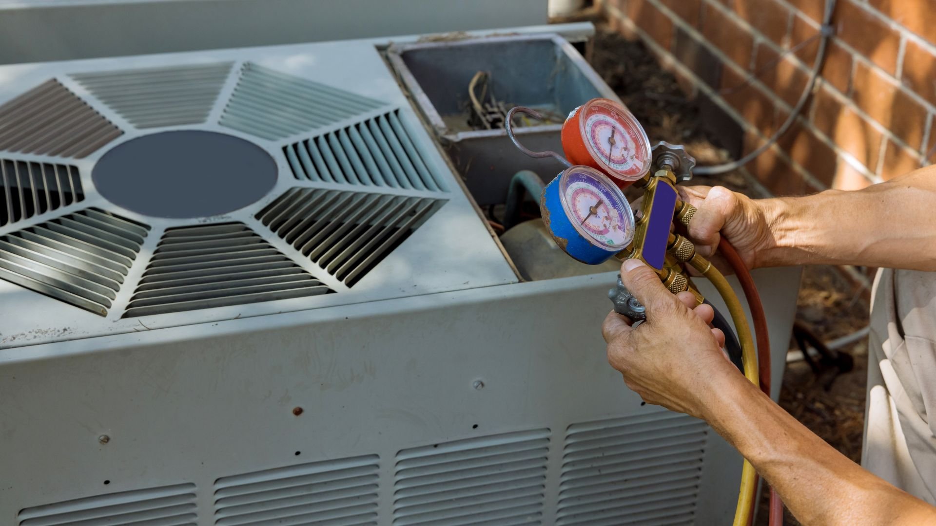 Technician checking pressure on air conditioning unit with manifold gauge